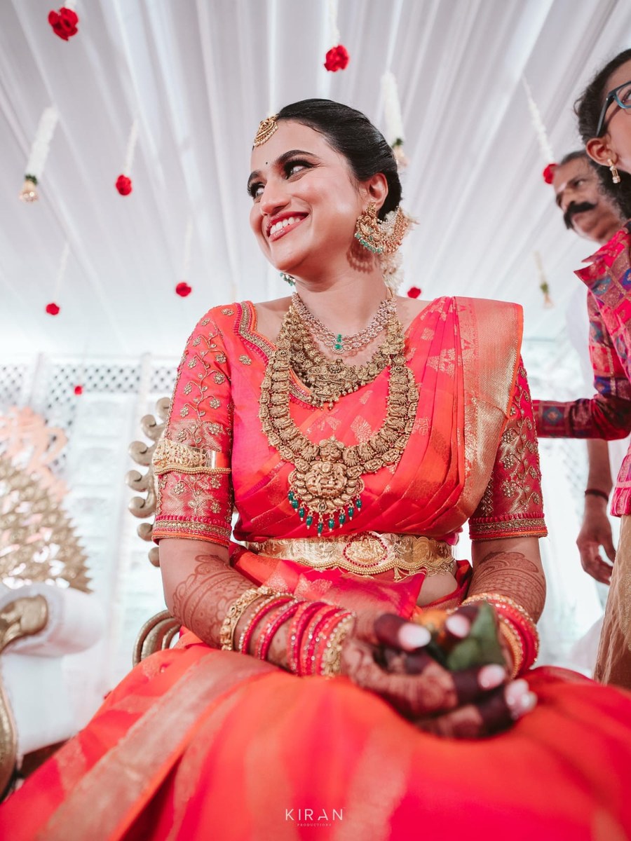 Bride in orange-pink silk saree blouse by Hello Beautiful Boutique
