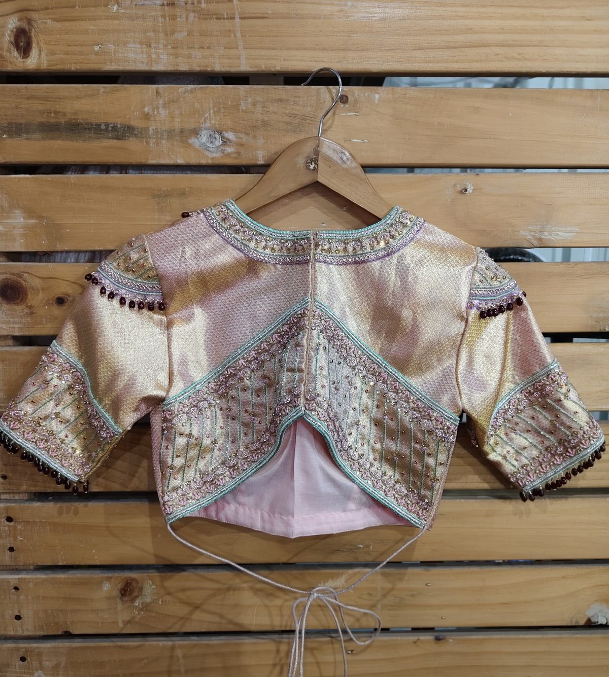 Back view of blush gold blouse with beaded embroidery and deep back cut